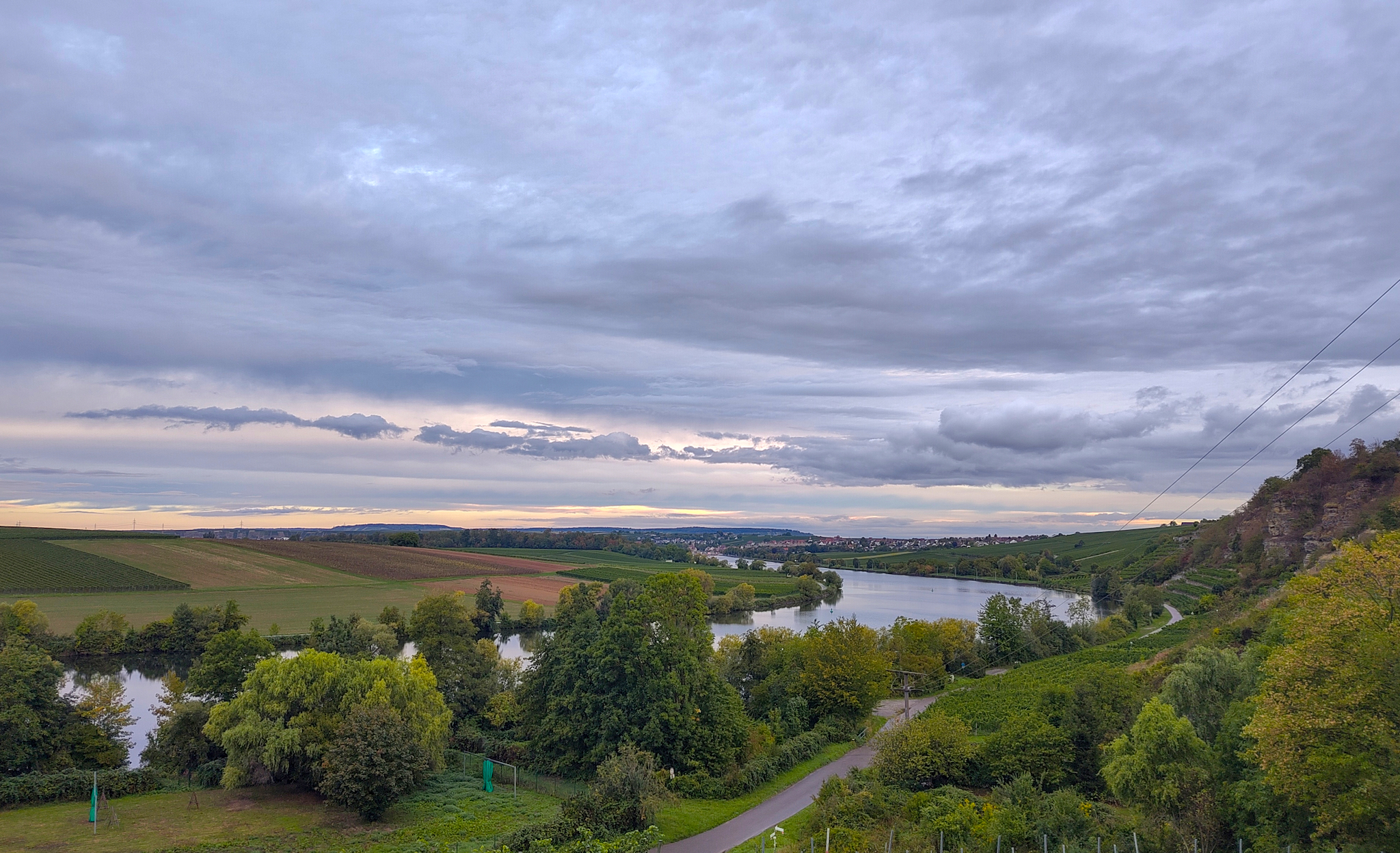 Die Neckarkurve vor Lauffen am Neckar. Am rechten Bildrand sieht man den Krappenfelsen. Dramatische Wolken ziehen durch die Szene.